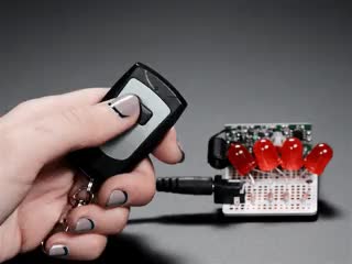 Hand pressing button on Keyfob 2-Button RF Remote Control and controlling LEDs on a project