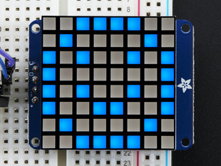 Close-up of Adafruit Small 1.2" 8x8 Blue LED Matrix w/I2C Backpack assembled and powered on. A blue graphic smiley is displayed.