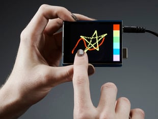 White hand holding a 2.8" TFT Touch Shield for Arduino w/Capacitive Touch while drawing a swiggling line and a star on the display. 