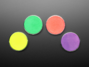 Topdown sot of four neon fluorescent paint discs in yellow, green, pink, and purple.