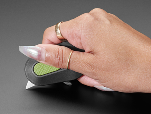 Manicured hand holding pocket cutter with blade extended.