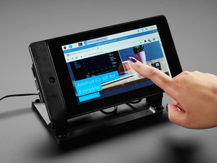 Angled shot of assembled and powered on Smarti Pi Touch stand for Raspberry Pi. A finger with a purple manicure is about to press the touchscreen.