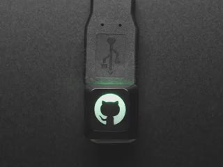 Close-up Video of black keycap with a cat-octopus character glowing rainbow colors.