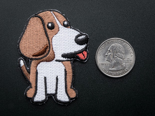 Embroidered badge in the shape of sitting BeagleBone dog.Dog is brown and white with red detail for tongue. Shown next to a quarter for scale.  