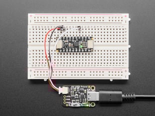 Overhead shot of a half-size breadboard connected to a UPDI board and an AtTiny breakout board. the LEDs light up green on both boards.