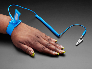 Angled shot of a Black hand with a green leopard-print manicure wearing a blue anti-static wrist strap.