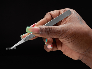 Lifestyle image showing the tweezers picking up a microchip.