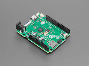 Angled shot of green, credit card-sized microcontroller with stacking headers.