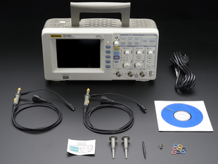 Oscilloscope with probes detached surrounded with accessories.